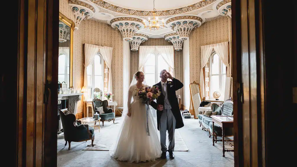 Bride and her father walking through a panelled doorway at Grittleton House