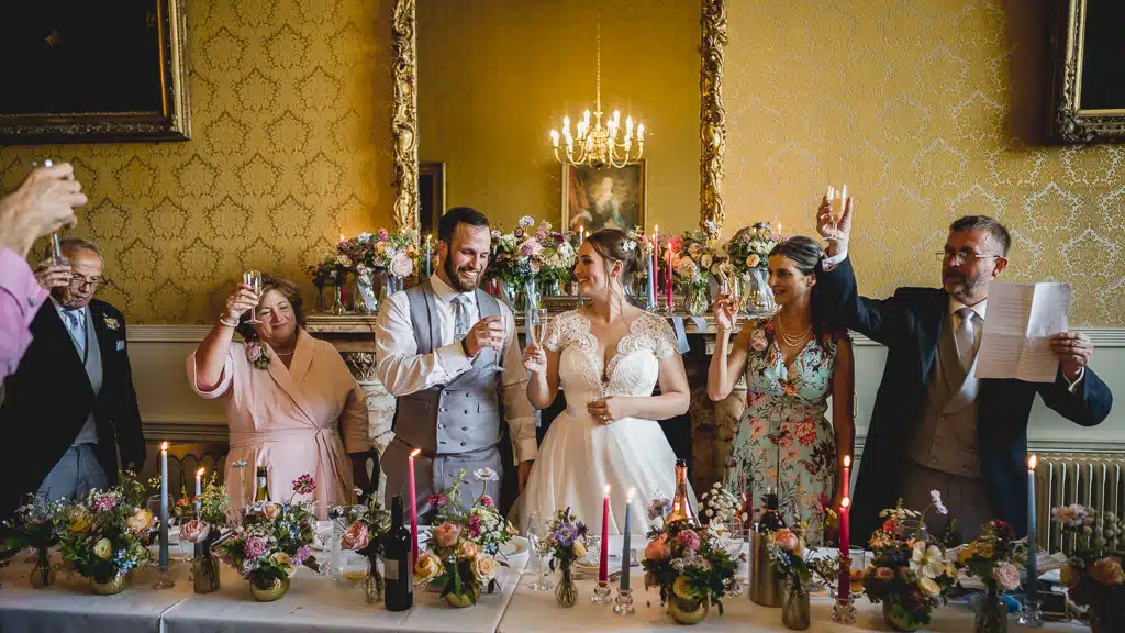 Guests cheering during speeches in the candlelit dining room at Grittleton House