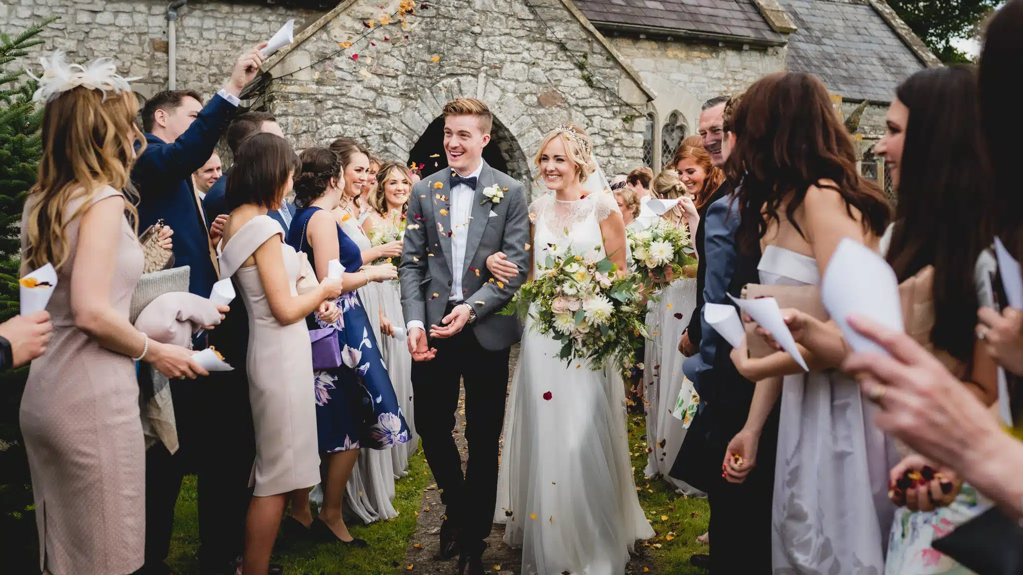Luxury-wedding-photography-at-Sant-Ffraed-House Bride and groom walk out during confetti toss after getting married at Elmore Court