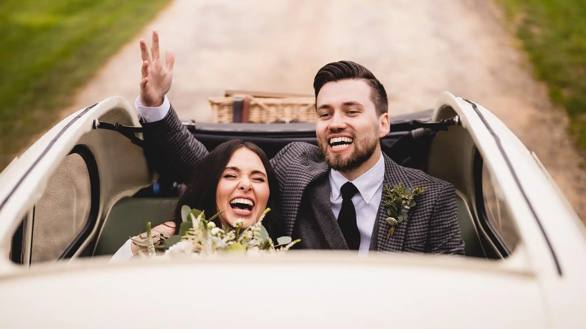 Abigail and Lewys cheering from the vintage car on the drive
