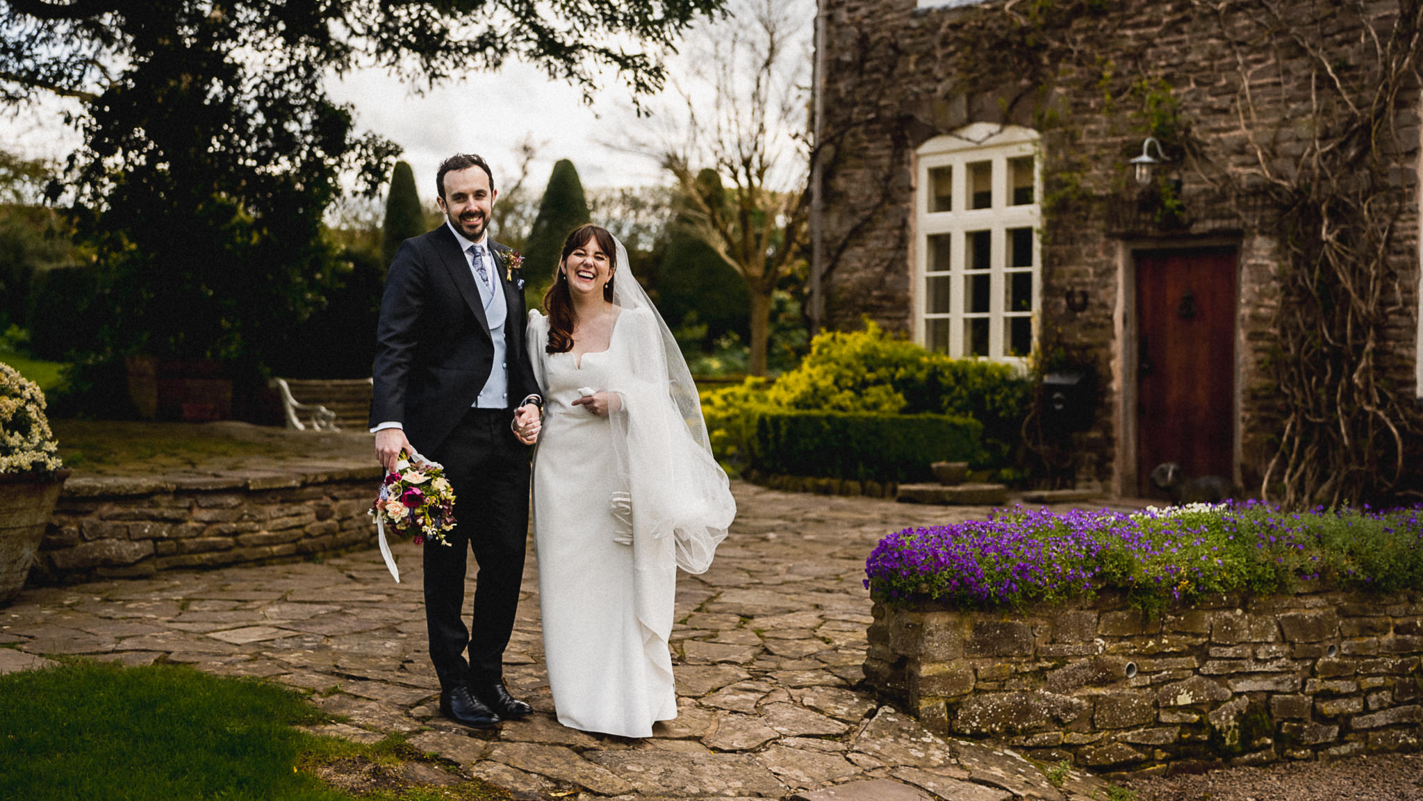 Bride and groom in front of the stone facade of Dewsall Court, Herefordshire