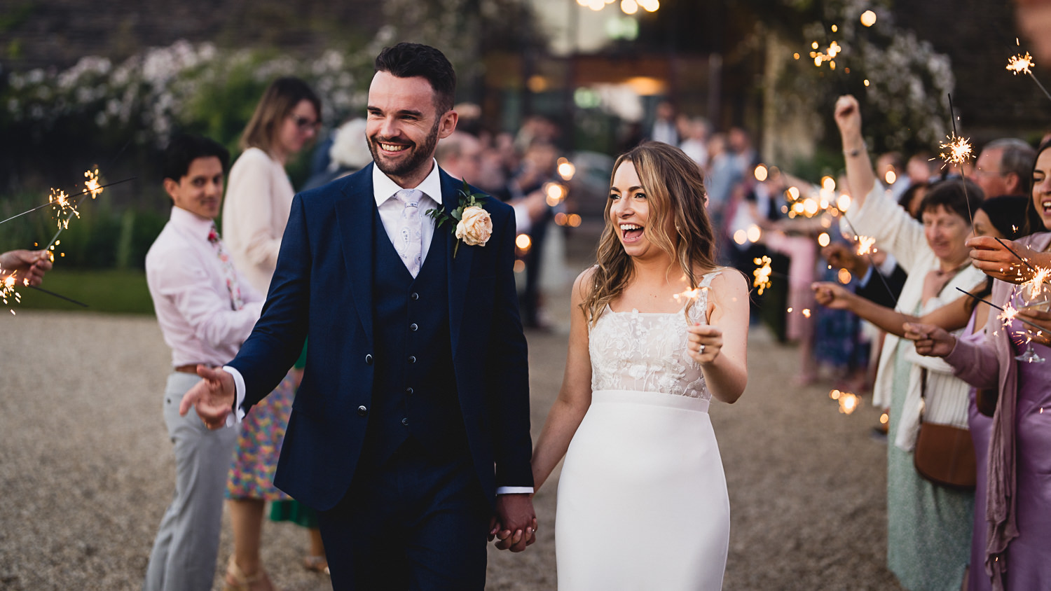Rachel and Cameron walking through sparklers outside the Great Tythe Barn