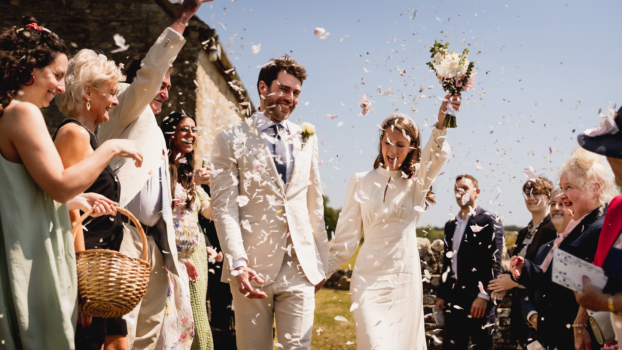 Bride and groom showered with confetti in the churchyard at Swinbrook