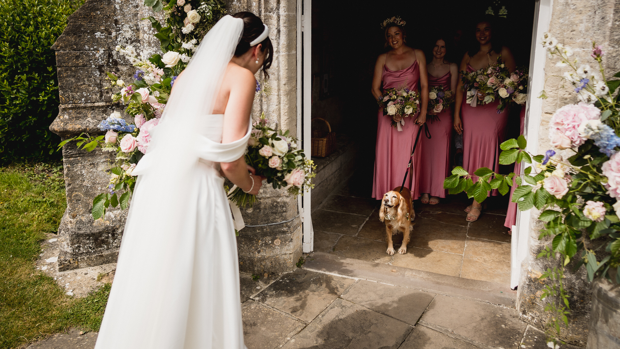 Bride pausing at the church door as her bridesmaids wait inside, Wiltshire