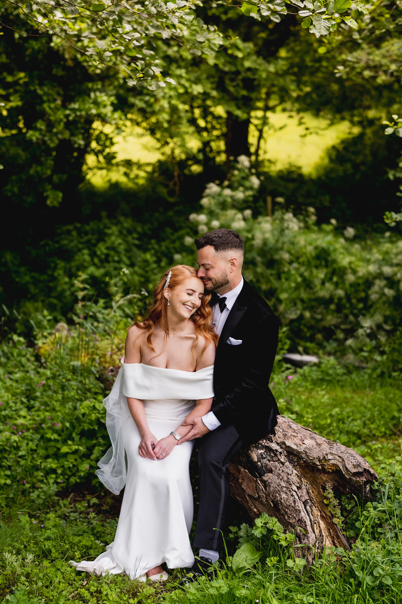 Couple sitting together on a log in a woodland garden
