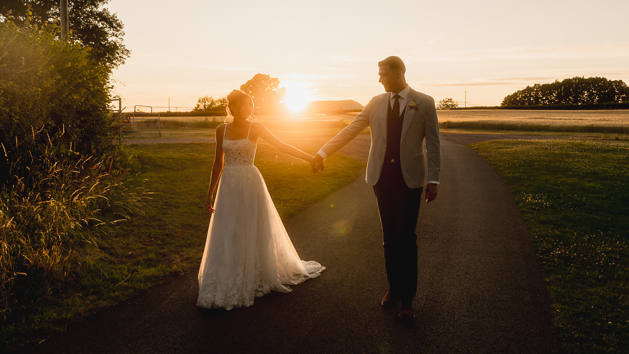 Couple walking hand in hand along a lane at sunset near Llantilio House