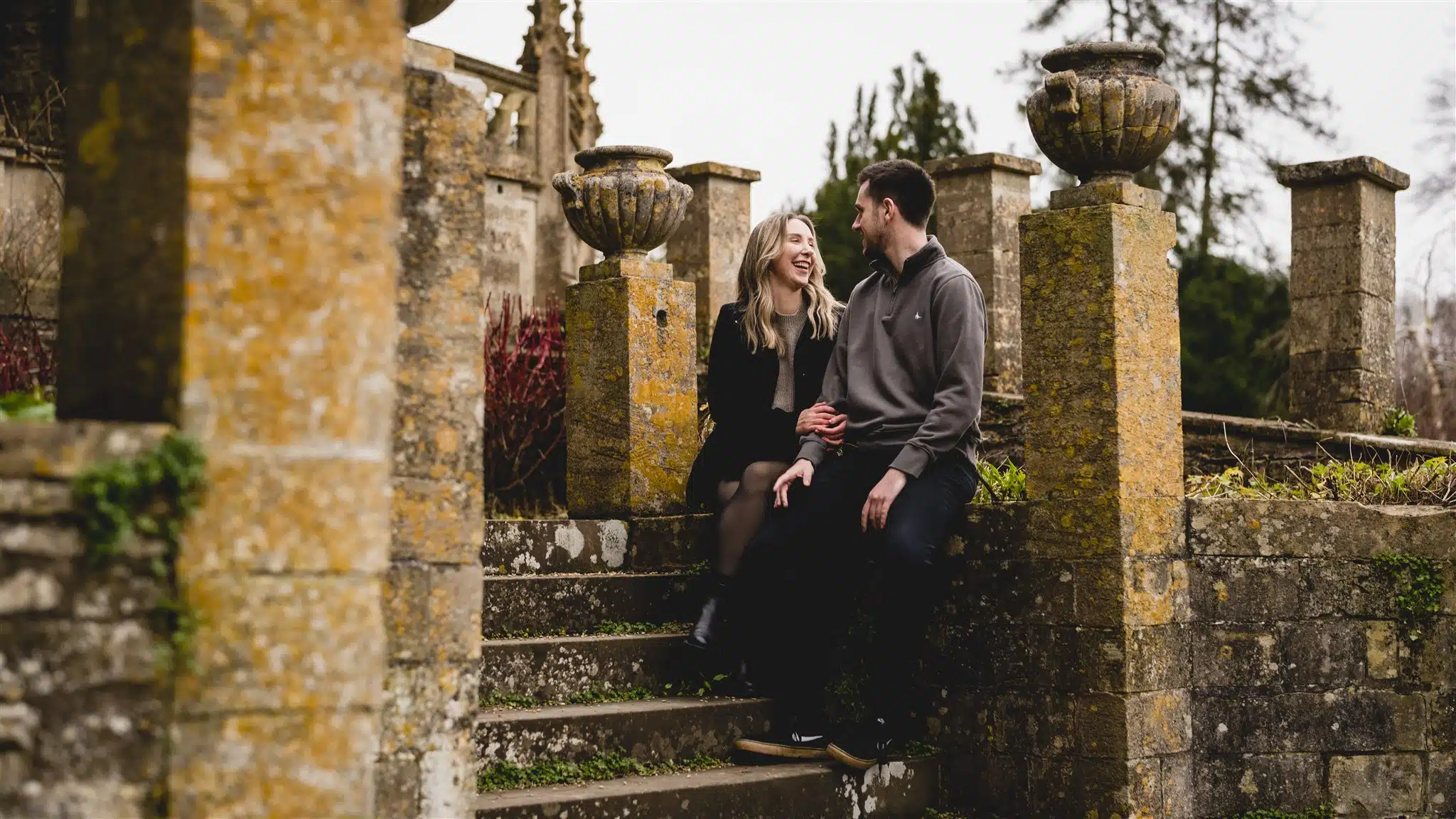Couple sitting together on old stone steps in Castle Combe, Wiltshire