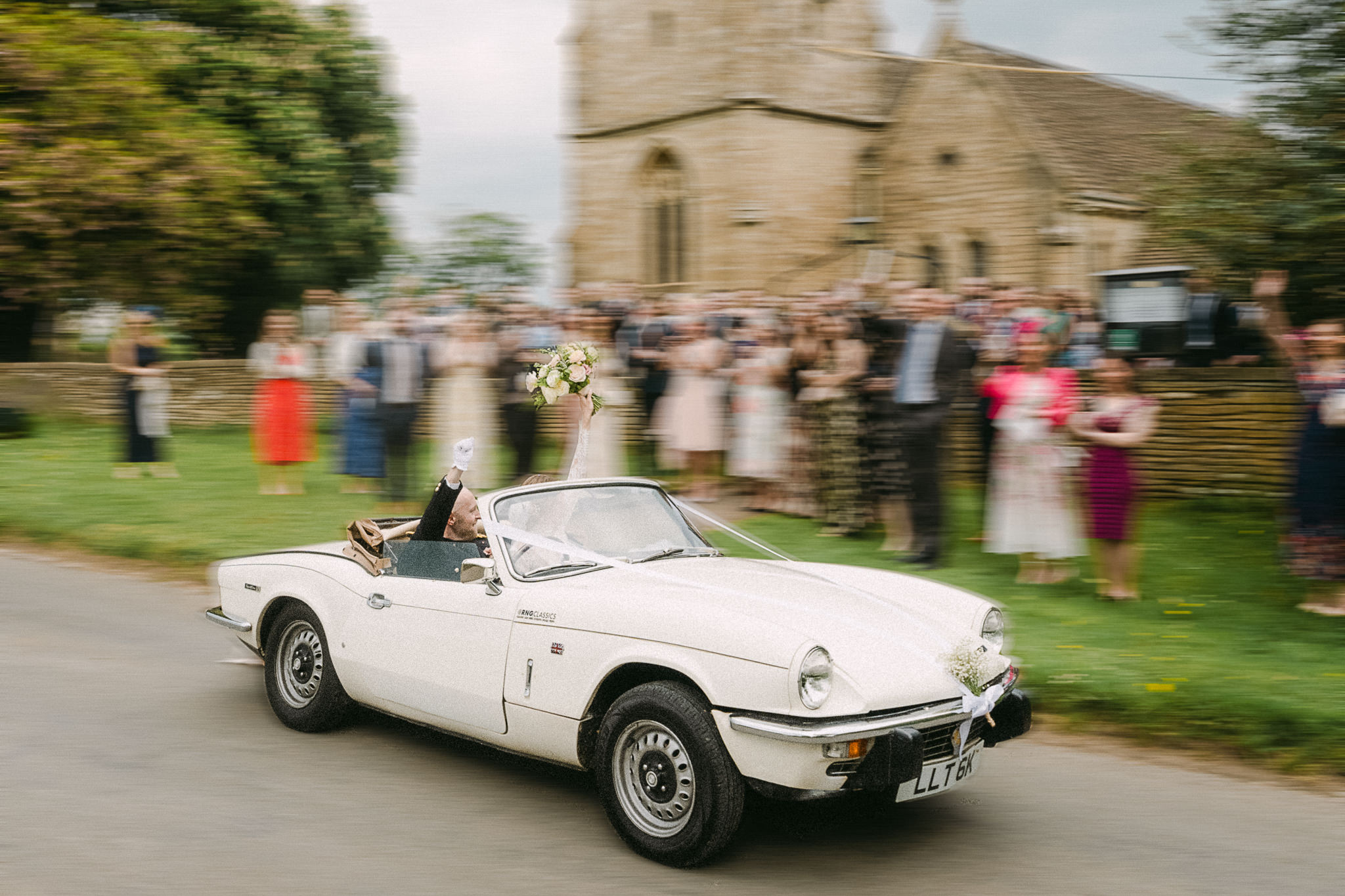 Newlyweds leaving church in a classic white car