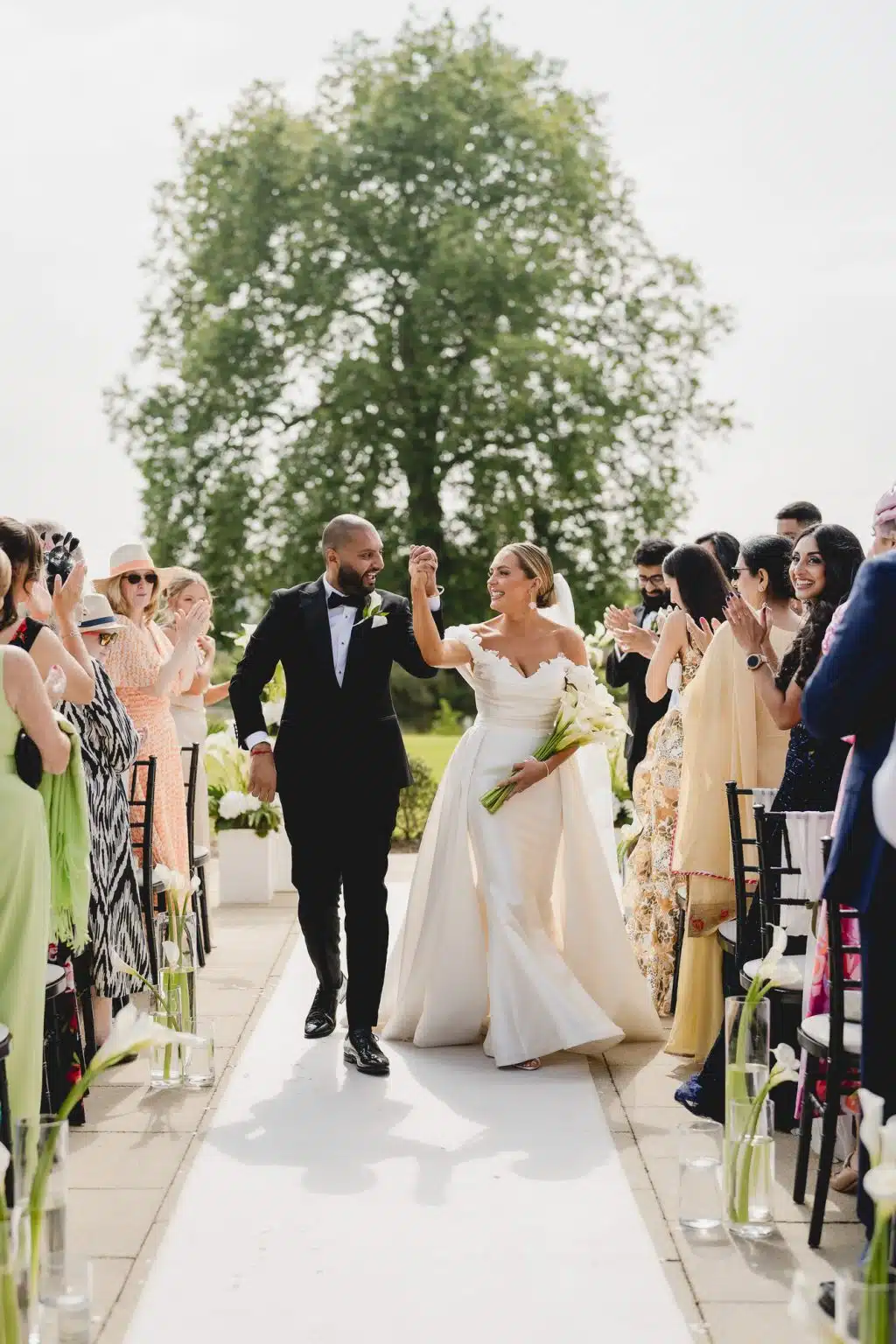 Bride and groom celebrating hand in hand as they walk back down the aisle