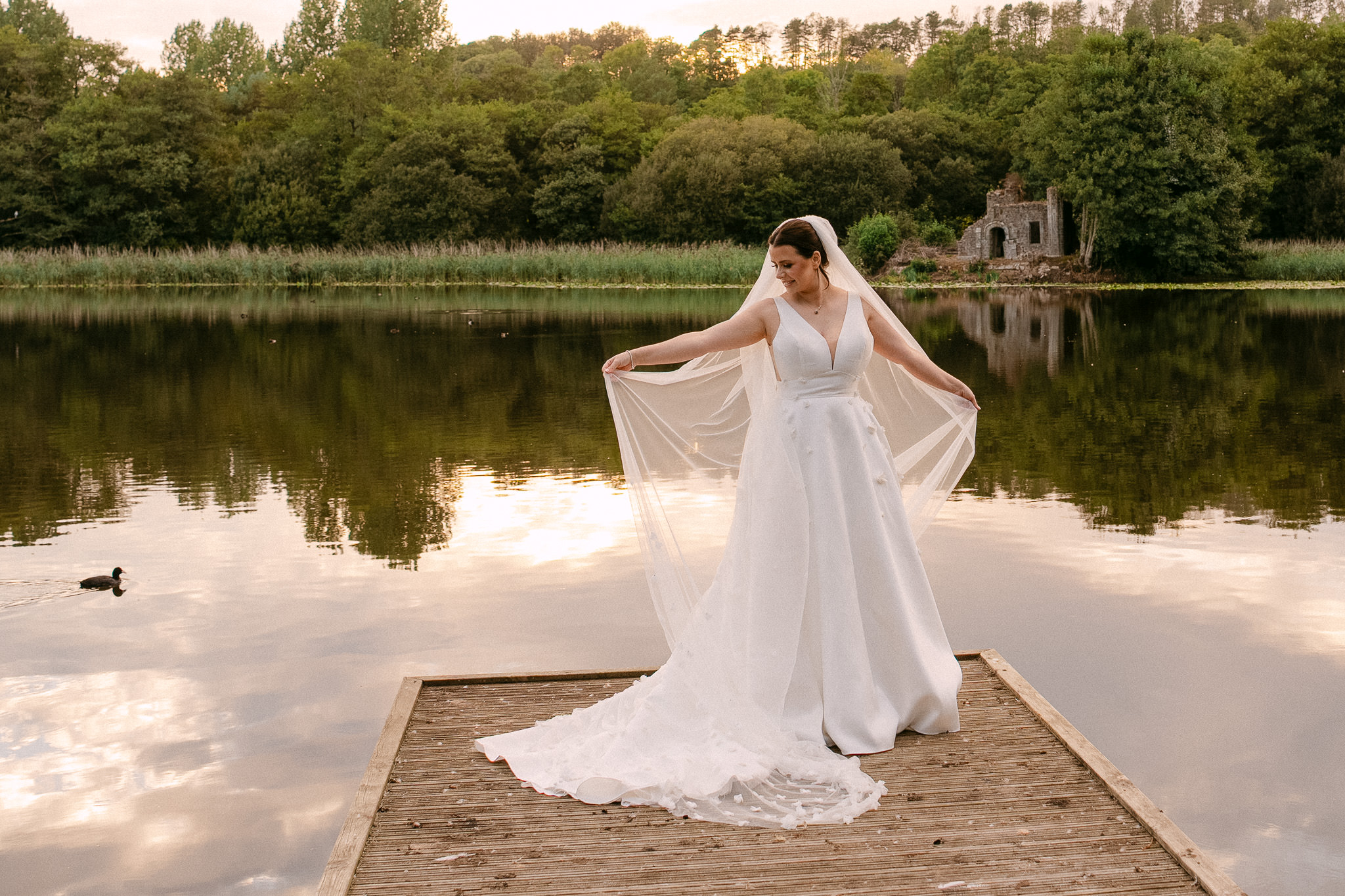 Bride on the jetty, the lake and the woods reflected around her