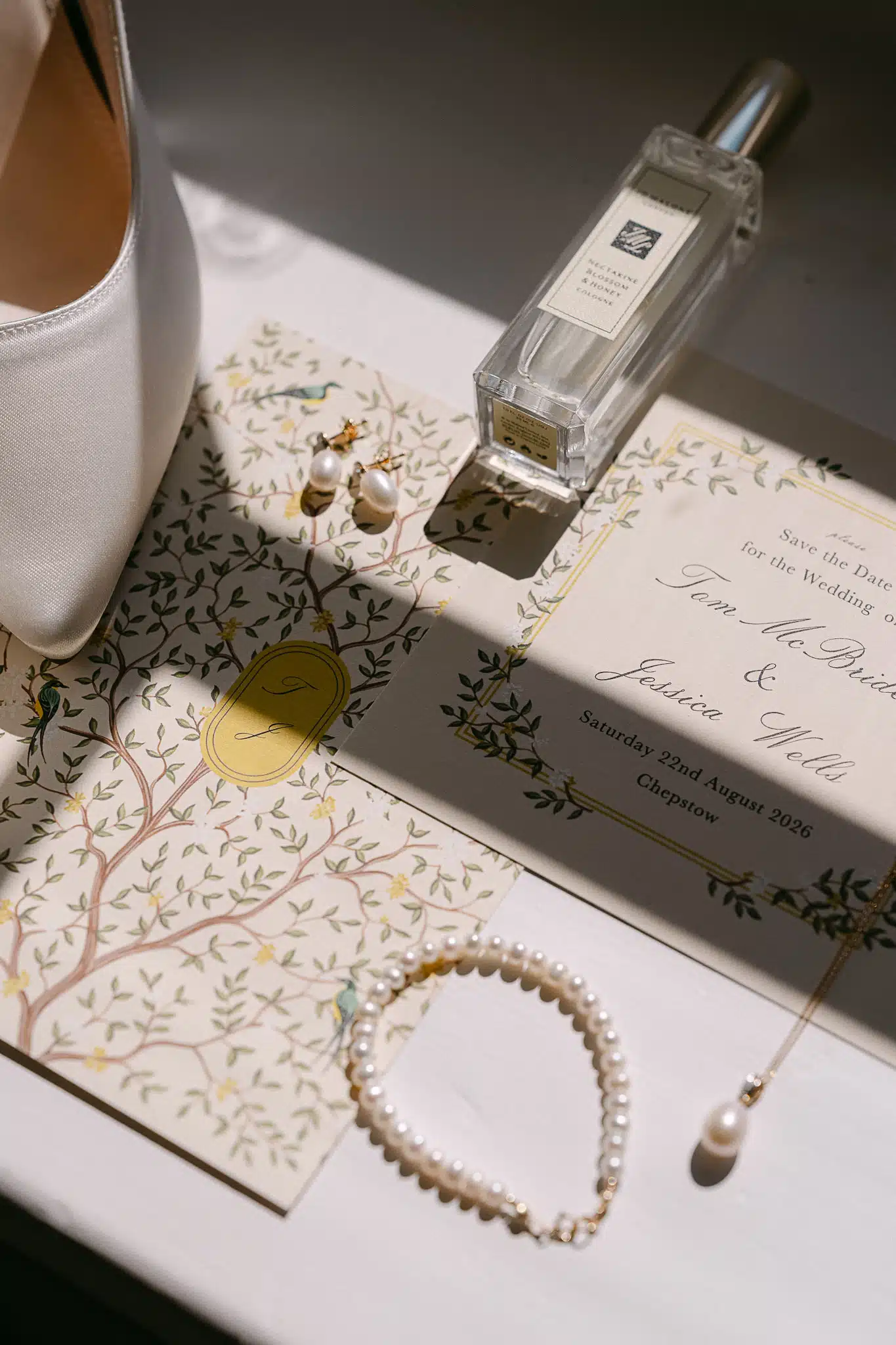 Jess and Tom’s invitation, shoes, perfume and pearls laid out in the morning light