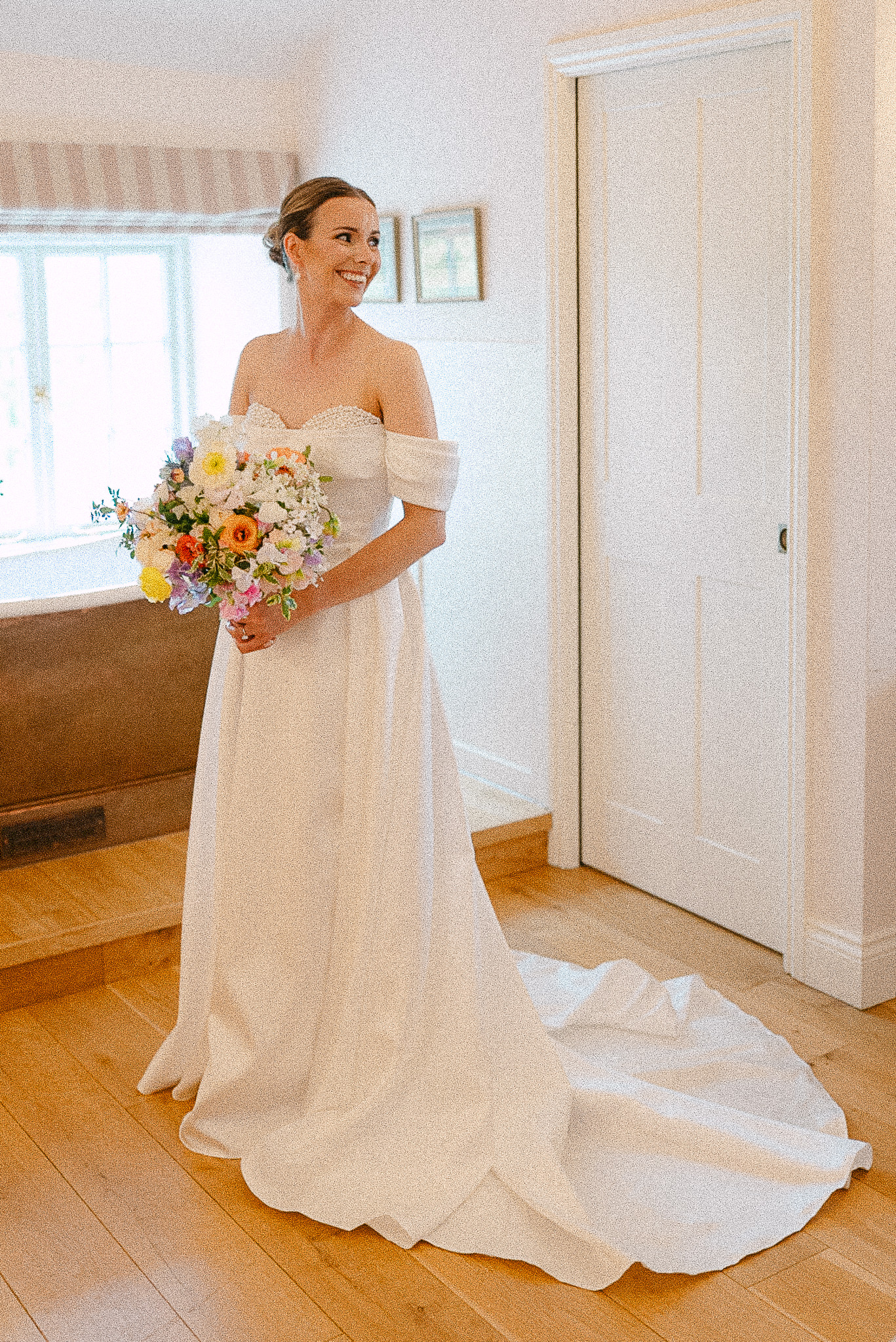Bride holding her bouquet in a sunlit bedroom