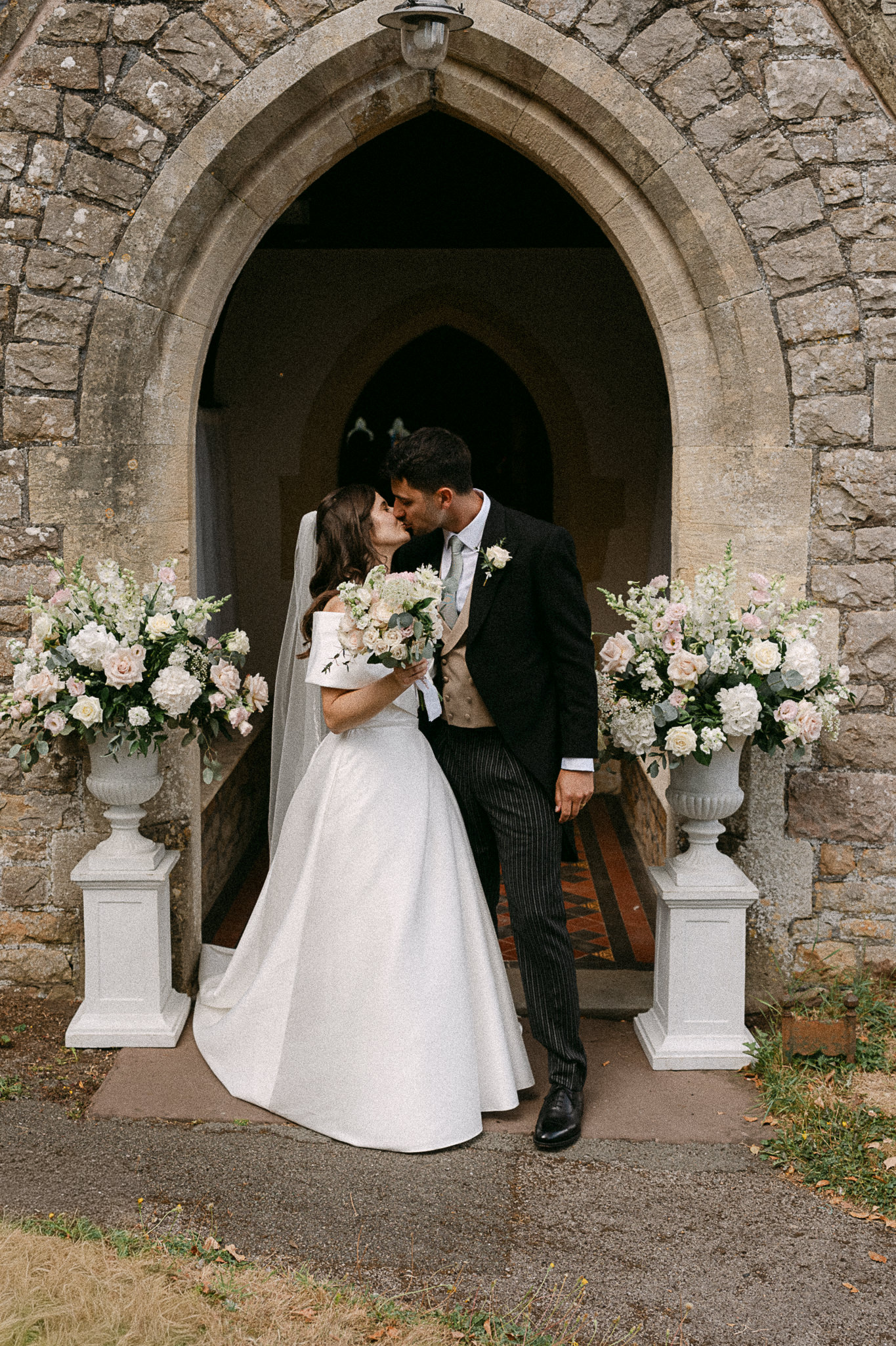 Newlyweds kissing in the arched doorway of a small church