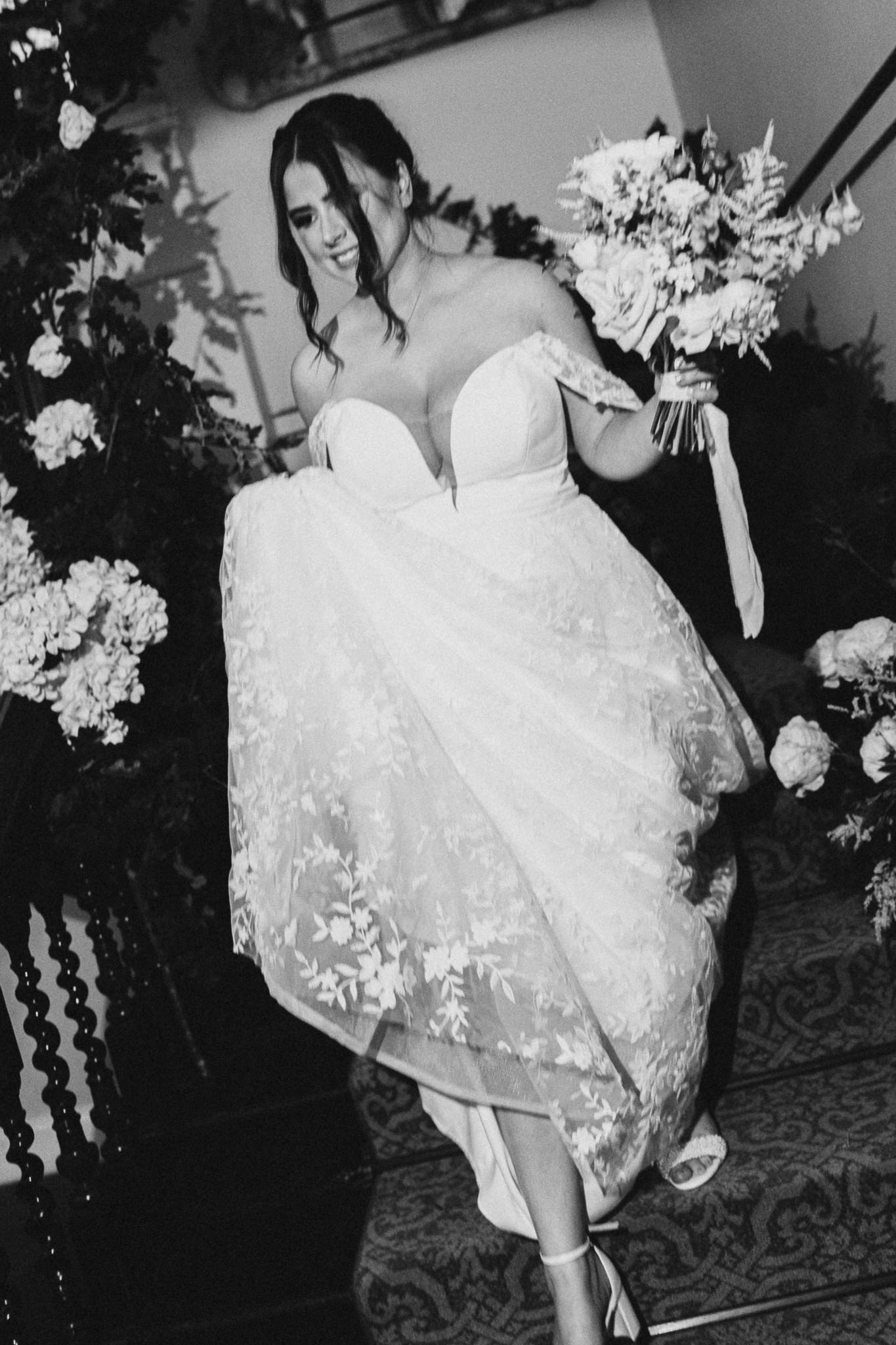 Bride on the stairs with her bouquet, in black and white