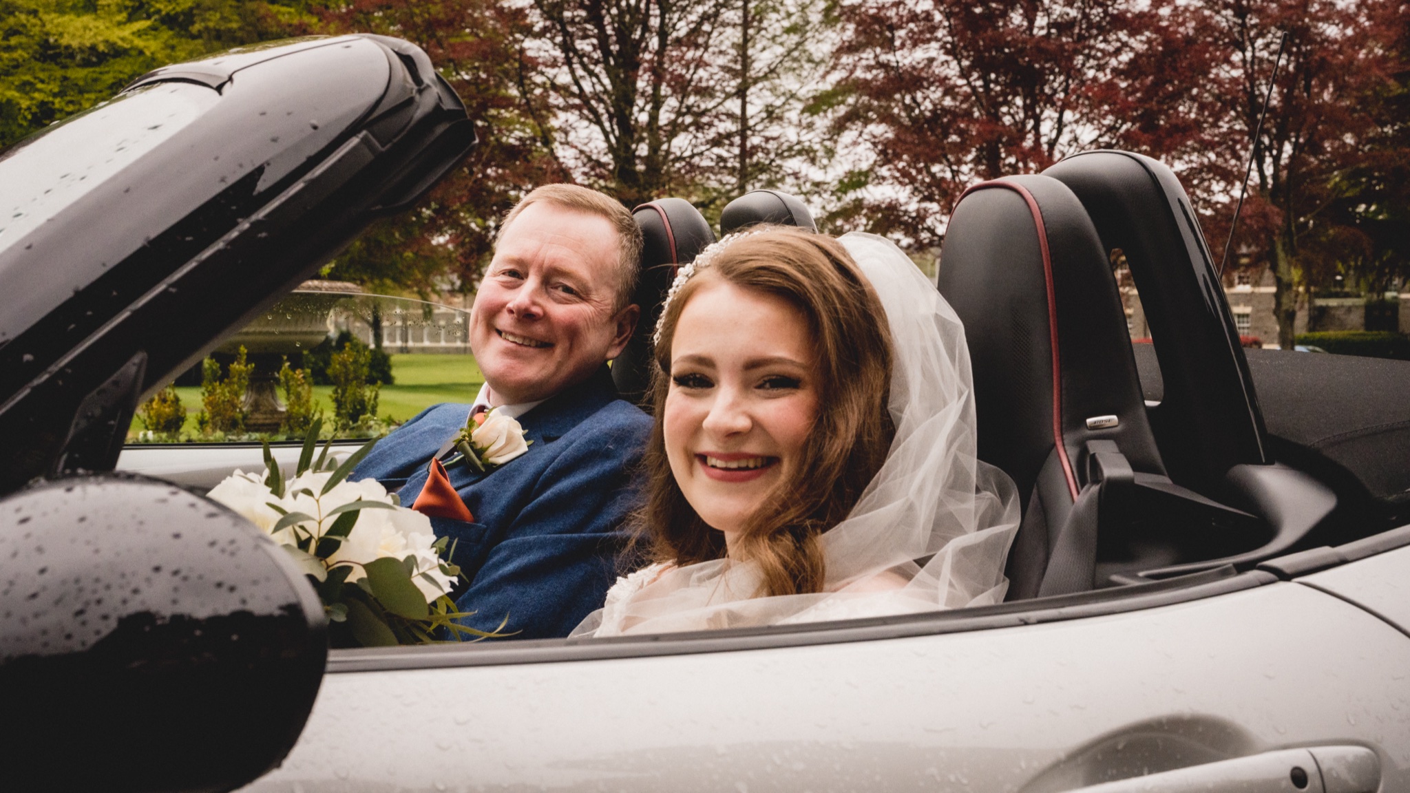 Bride and her father arriving in an open-top car