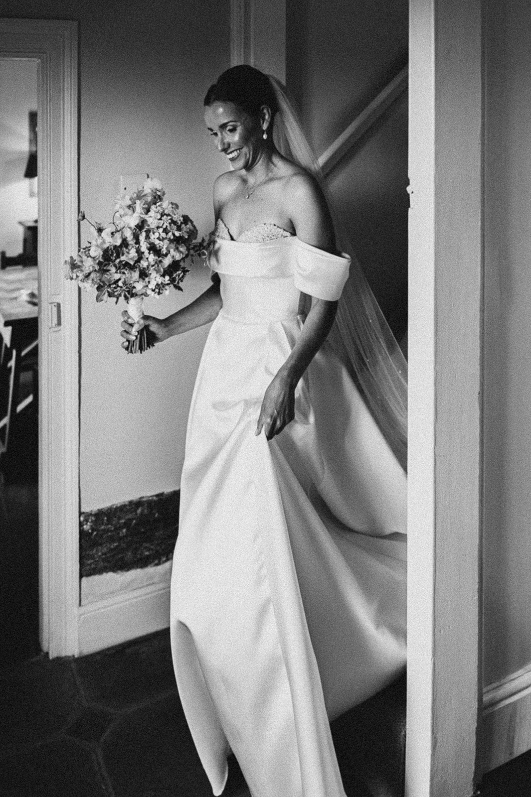 Olivia stepping out through the farmhouse door, in black and white