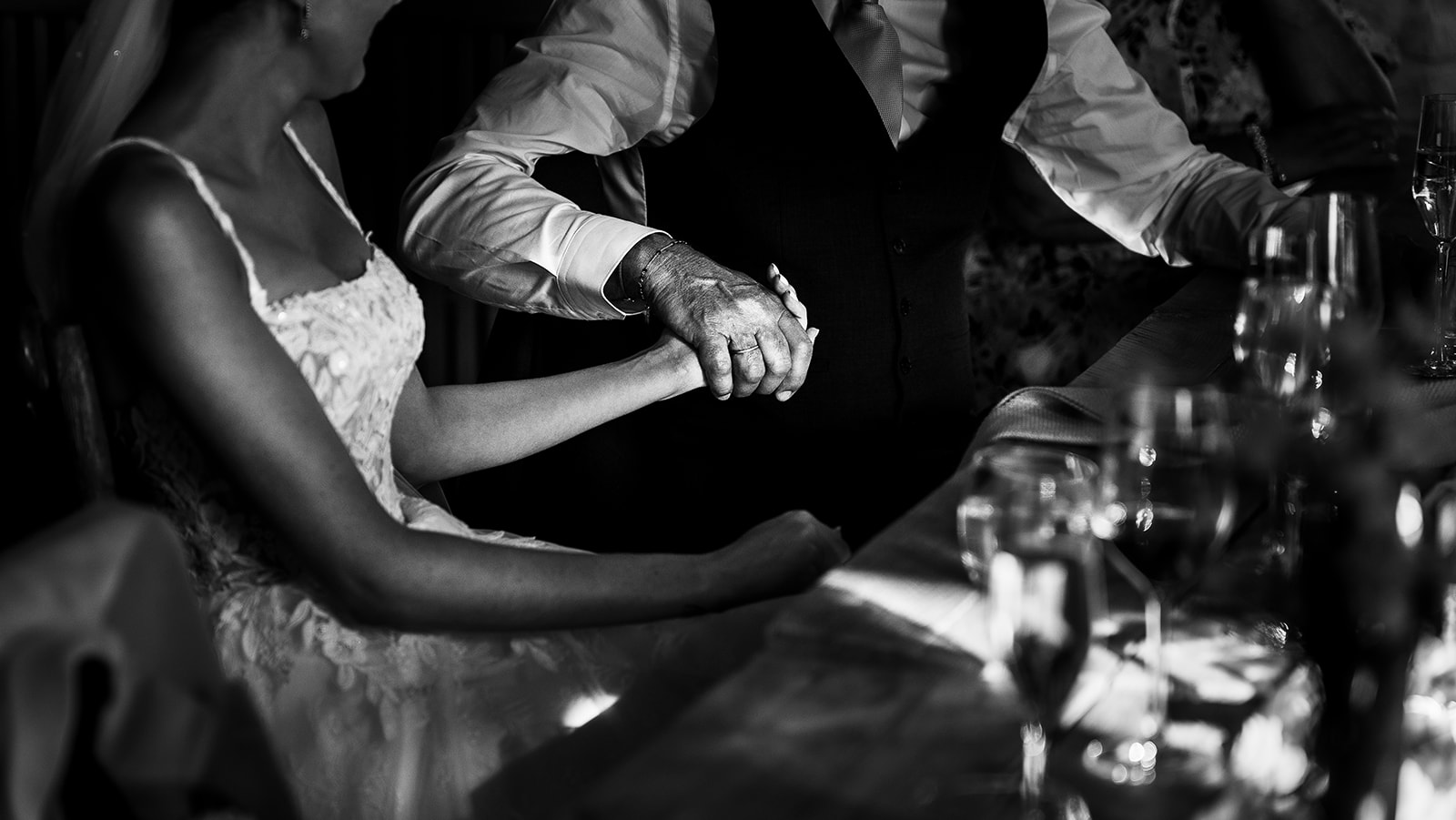 Rosie and Ben holding hands at the table, in black and white