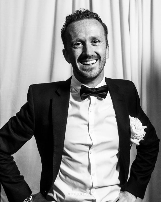 A wedding guest in black tie grinning at the camera