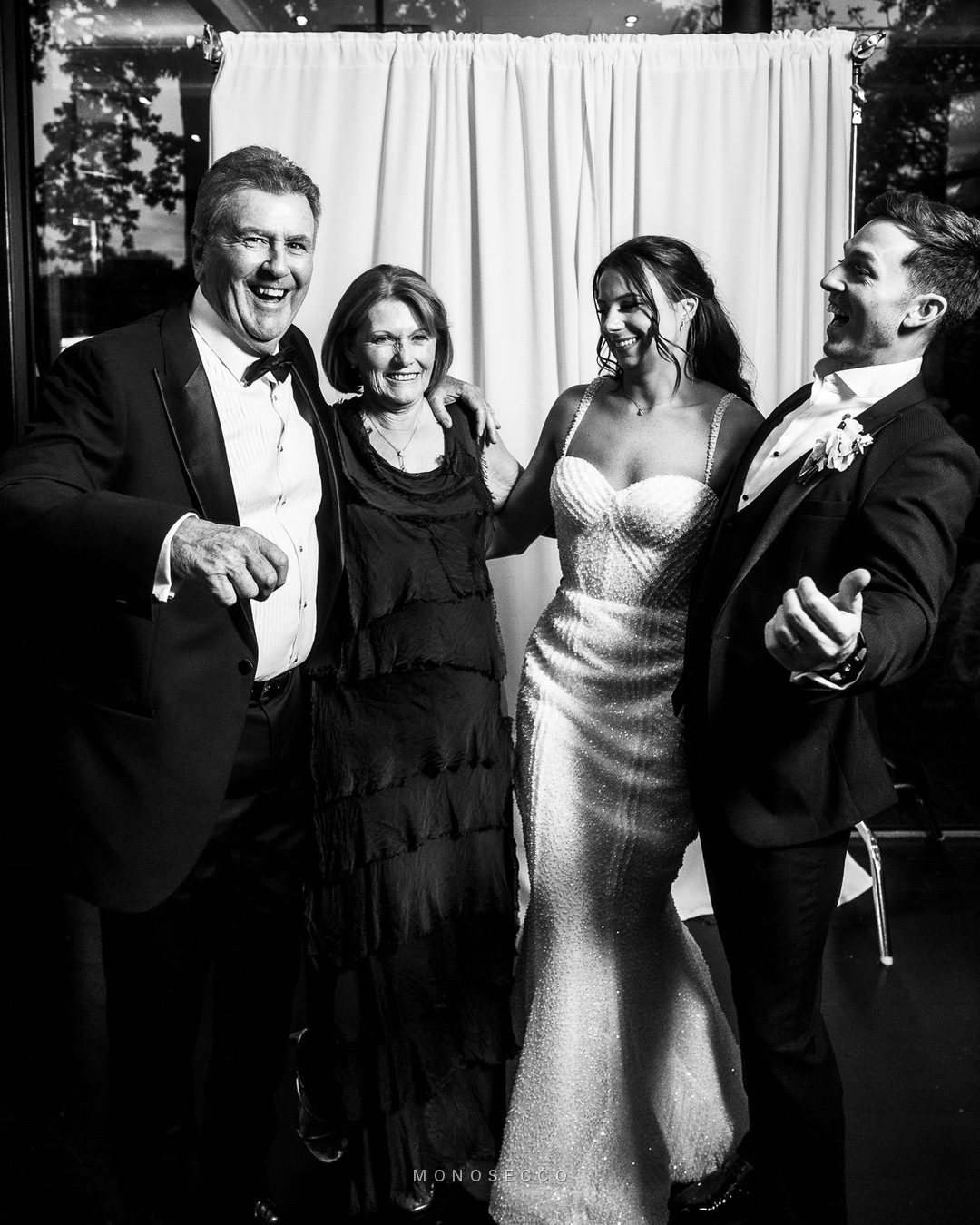 Parents and the newlyweds together in front of the backdrop