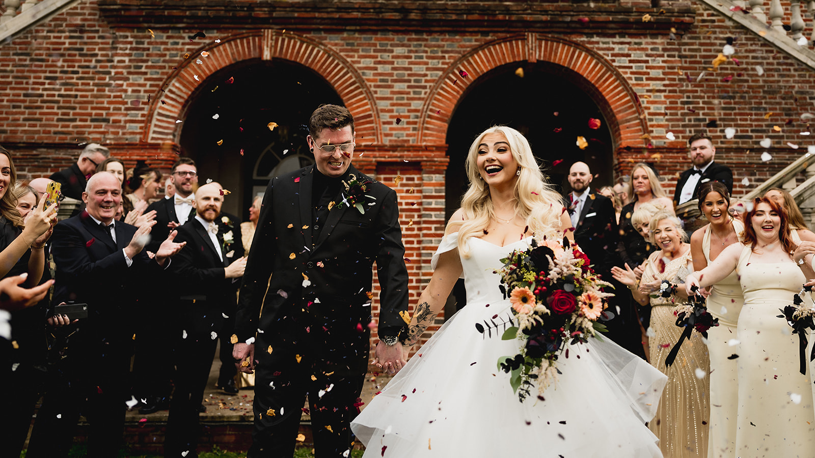 Confetti thrown over Karrie and Rafe beneath the brick arches