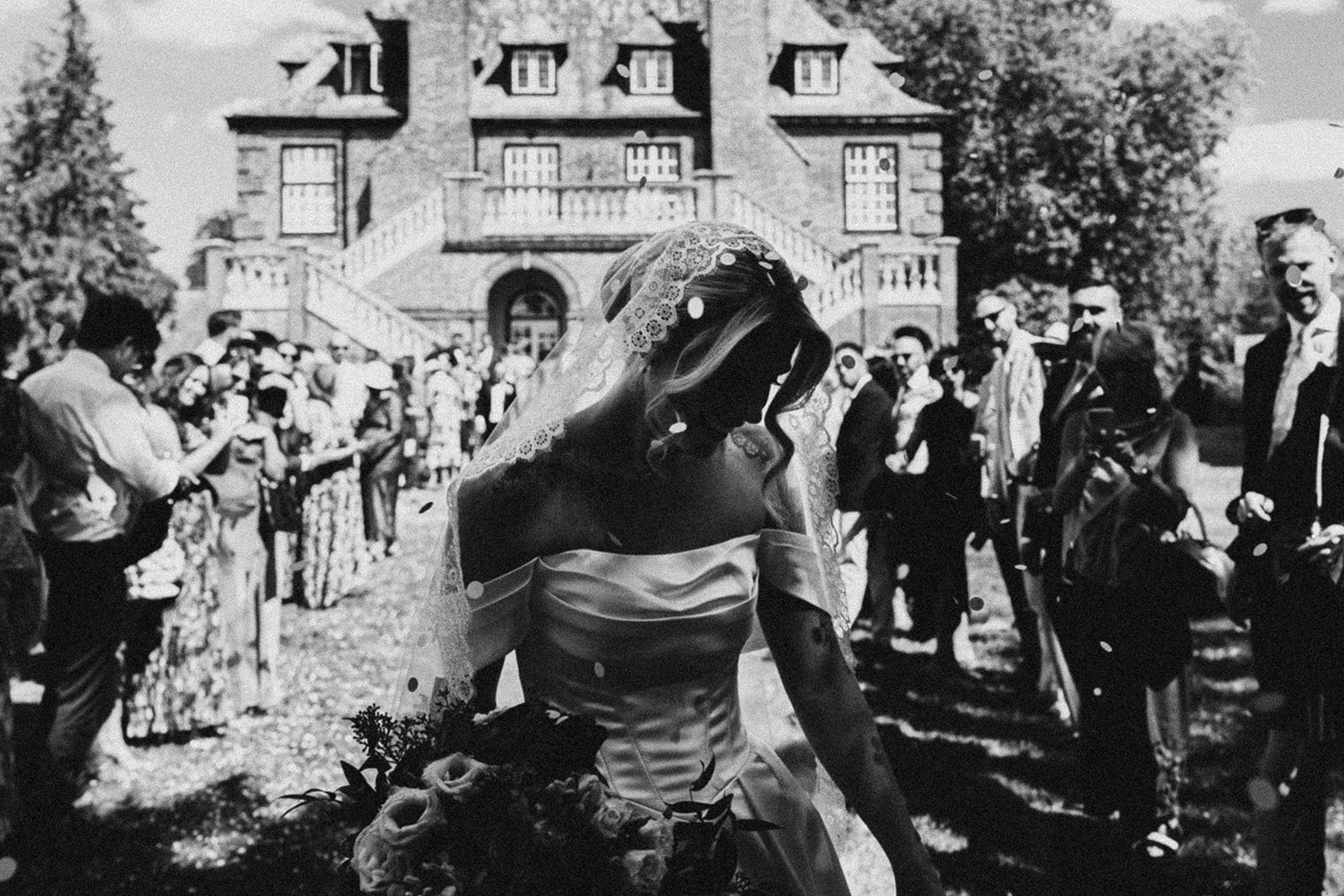 Kate walking through her guests and the confetti, in black and white