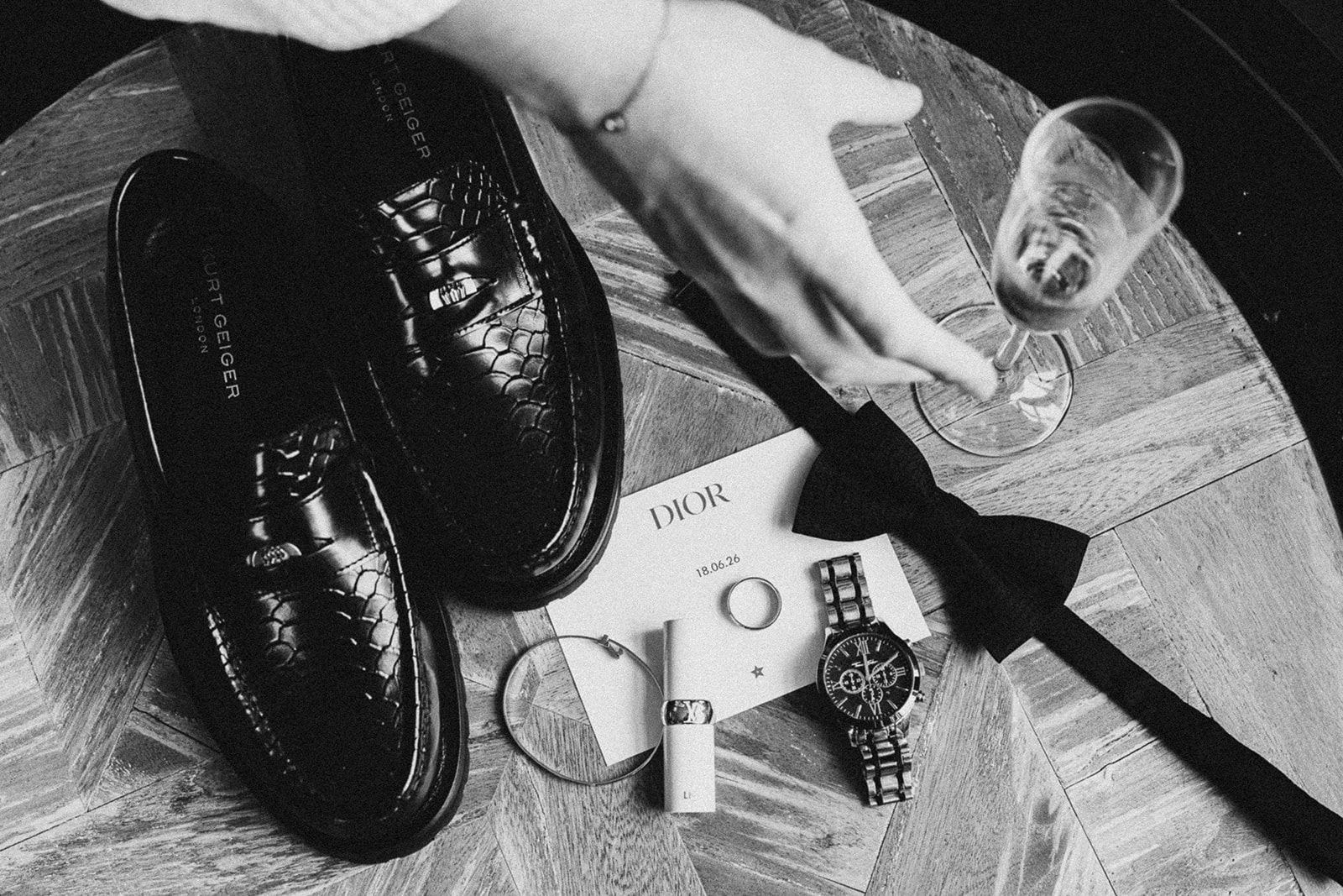 Shoes, watch and bow tie laid out, in black and white