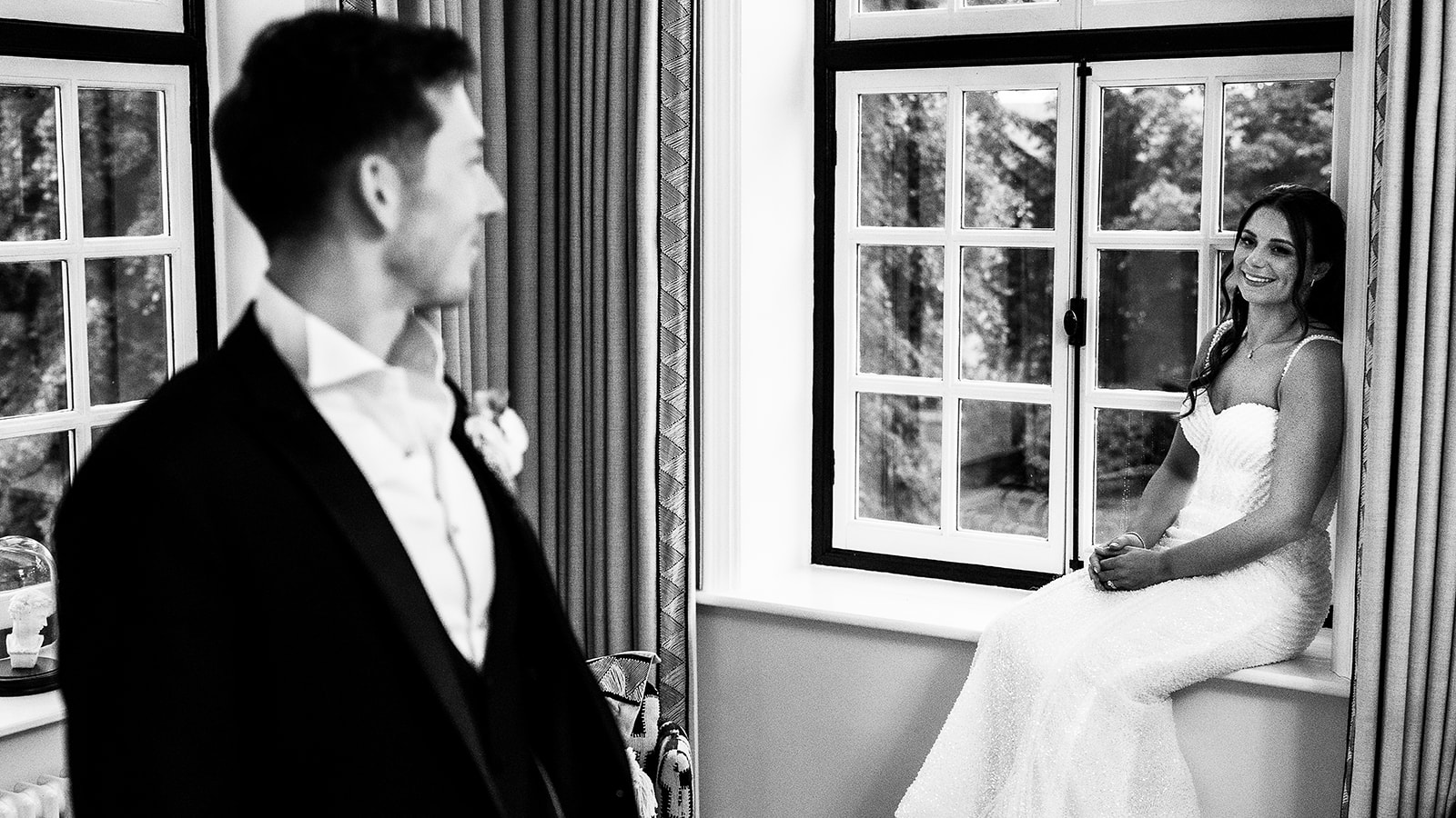Nick looking across at Sophia by the window, in black and white