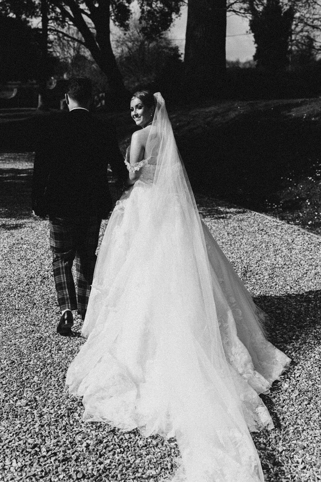 Eilir walking across the gravel in her dress, in black and white