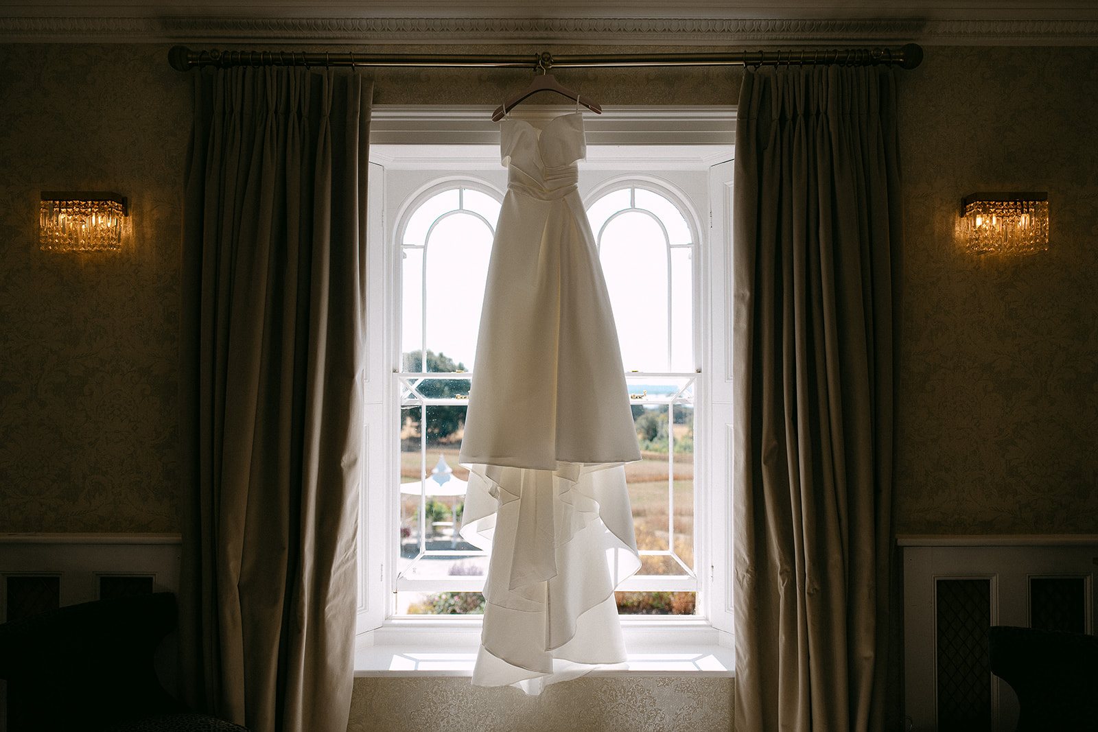 The wedding dress hanging in the bedroom window