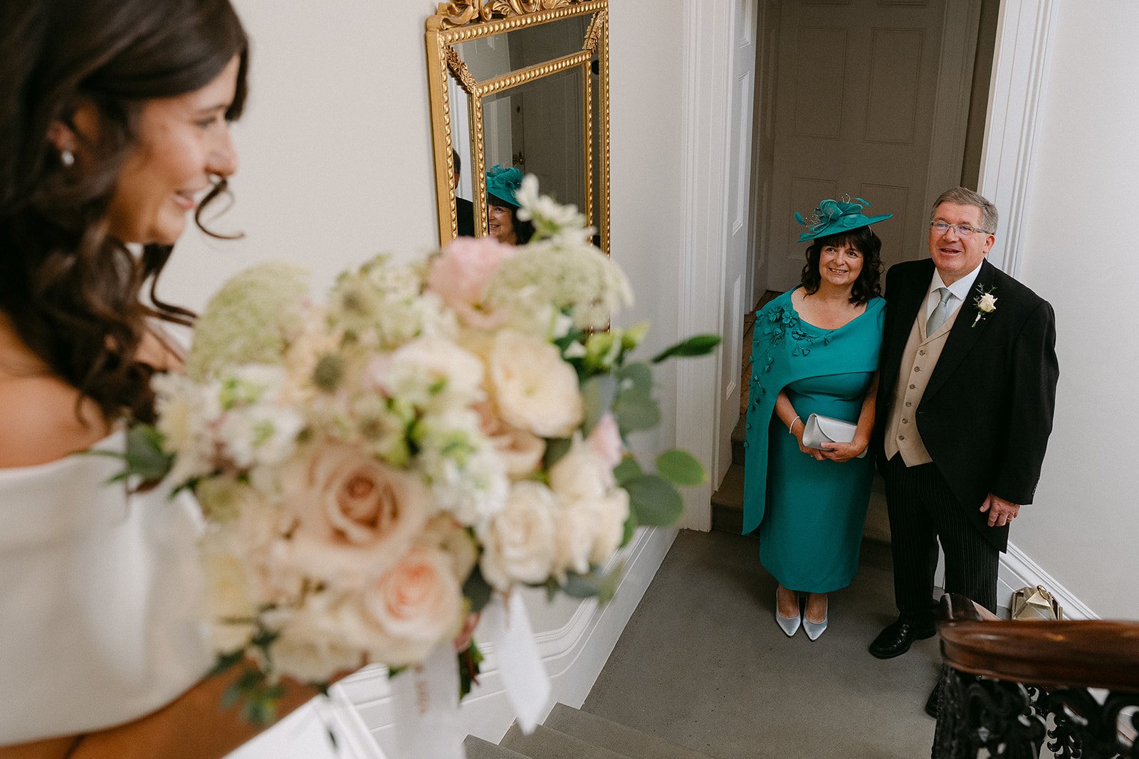 Jess with her bouquet as her parents wait by the mirror
