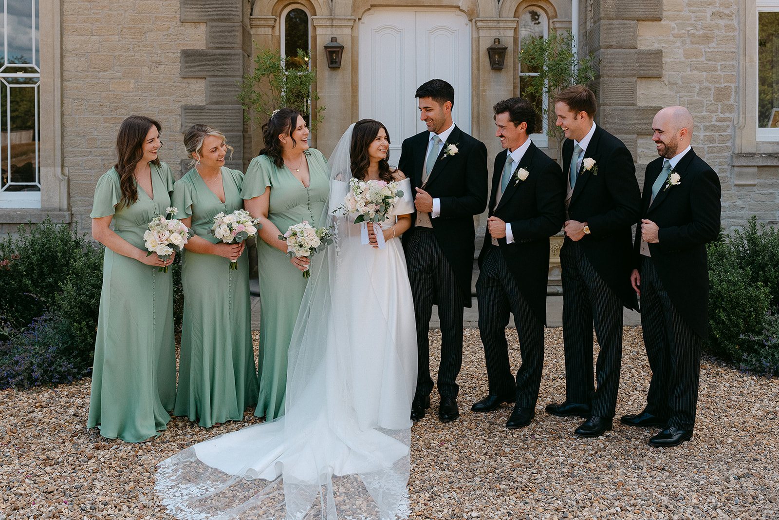 Jess and Tom with their bridesmaids and groomsmen in front of the house