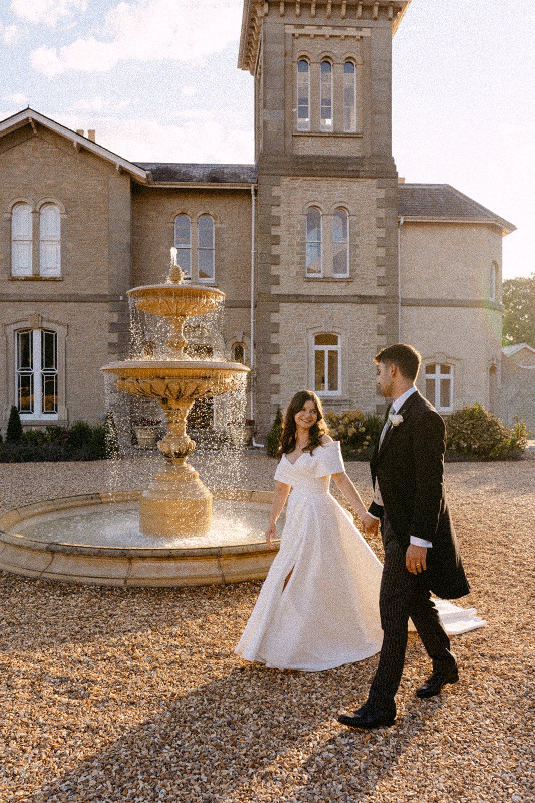 Jess and Tom walking past the fountain on the front drive