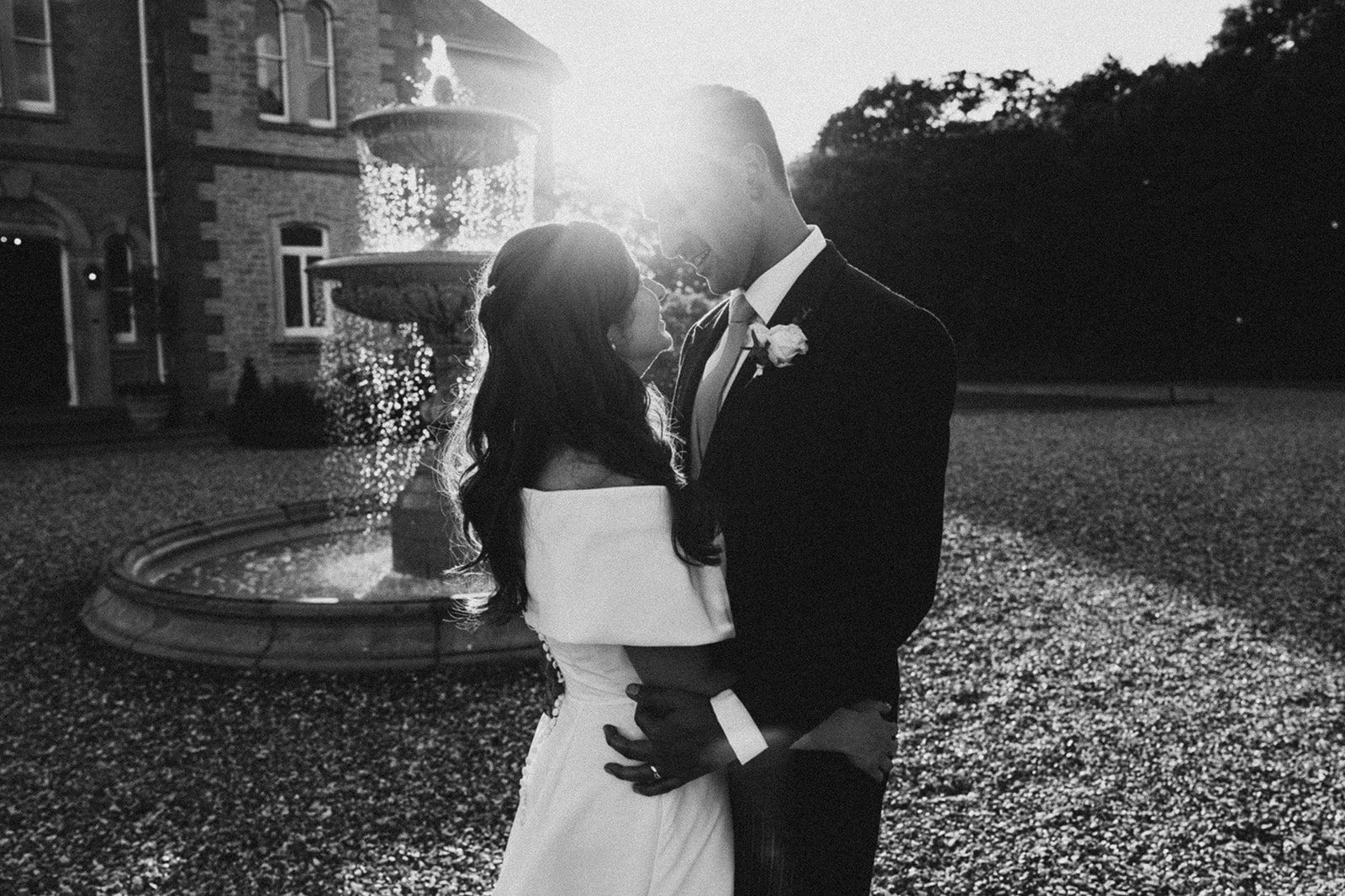 Jess and Tom kissing by the fountain, in black and white
